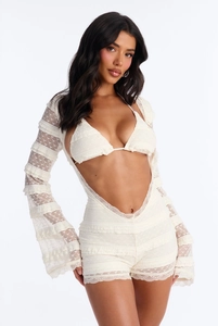 Détail de la texture en dentelle florale blanche sur l'ensemble bikini à manches évasées