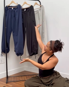 Three colors of drawstring wide leg pants in navy, black and grey displayed on a rack