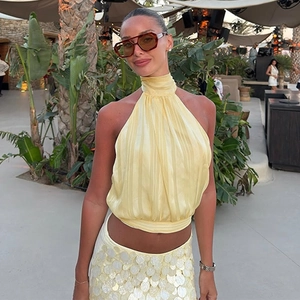 Detail of pale yellow halter top and sequined skirt set in a tropical resort setting