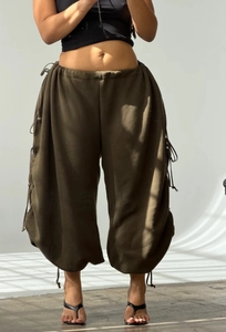 Detail of olive green wide-leg trousers featuring adjustable side drawstrings and loose fit