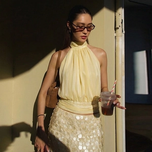 Detail of light yellow halter top with pleated neckline and sequined mini skirt