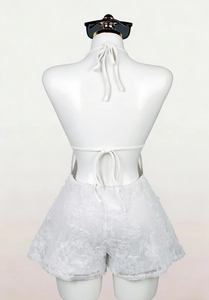 Detail of the white lace romper featuring an open back design with elegant tie-up ribbons