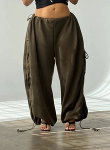 Detail of adjustable drawstrings and ruched fabric on dark olive green wide-leg pants