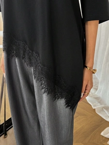 Close-up of elegant eyelash lace stitching on the asymmetrical hem of a black shirt