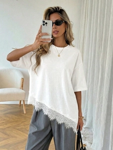 Detailed view of white oversized T-shirt with asymmetrical floral lace patchwork hem