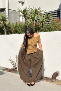 Detail of baggy wide-leg trousers with drawstring cuffs and pleated yellow crop top