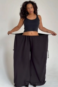 Detail showing the adjustable drawstring waist and oversized wide-leg cut of black trousers