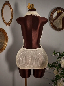 Detail of beige crochet knit halter dress showing hollow out mesh texture and backless design