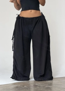 Detail view of black wide-leg trousers featuring adjustable side drawstring and ruched design