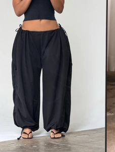 Detail of black baggy parachute pants featuring adjustable drawstrings and wide leg fit
