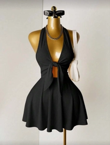Detail des schwarzen Neckholder-Minikleids mit tiefem V-Ausschnitt und modischem Bindeknoten