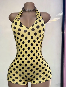 Dettaglio di una tuta halter gialla a pois con un'elegante collana a catena in argento