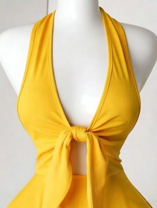 Detail eines hellgelben Neckholder-Kleids mit tiefem V-Ausschnitt und vorderem Knotendetail