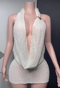 Detail of white crochet knit beach dress featuring a deep V-neck and golden strap hardware