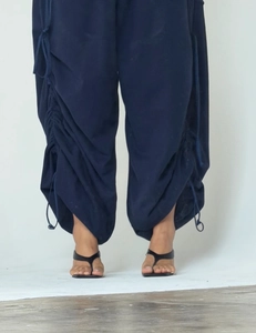 Detail of adjustable drawstring hem on dark blue loose-fitting parachute trousers