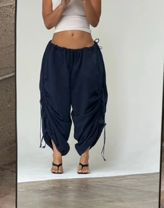 Detail of navy blue parachute trousers featuring adjustable side drawstrings and loose fit