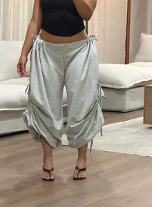 Detail view of grey wide-leg trousers with adjustable side drawstring and ruched texture