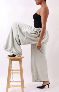 Detail of light grey wide-leg pants with adjustable drawstring waist and hem cords