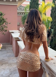 Detailed texture of champagne gold sequins on a party crop top and mini skirt set