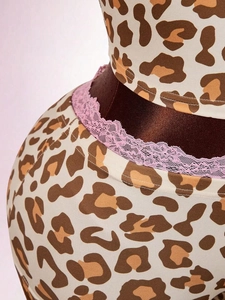 Detailed view of leopard print lingerie set with delicate pink lace trim and bow accent