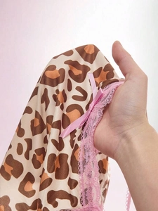 Detail of leopard print fabric with pink lace trim and a satin bow on a slim outfit
