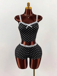 Women's black polka dot two-piece pajama set with lace trim and bow accent on mannequin