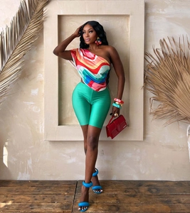 Detail of summer set with abstract one-shoulder print top and green biker shorts