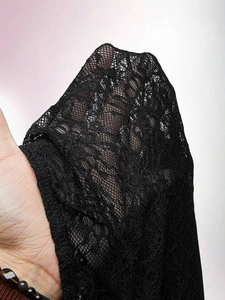 Detailed close-up of delicate black floral lace fabric with high transparency and texture