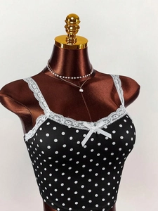 Close-up of black polka dot camisole with delicate white lace trim and a small bow detail