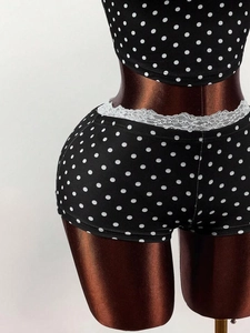 Detail of high-waist polka dot shorts with white lace trim and elastic knit fabric