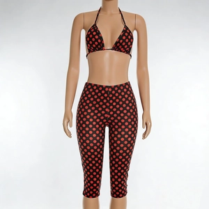Détail du legging court taille haute avec motif à pois rouges sur tissu noir