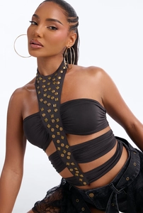 Dettaglio del crop top nero allacciato al collo con borchie dorate e spalline cave