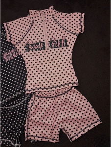 Detail of girls pink polka dot swimwear featuring Star Girl print and front zipper