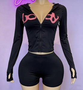 Detail of black hooded zip jacket and biker shorts set with thumbhole cuffs and pink logo
