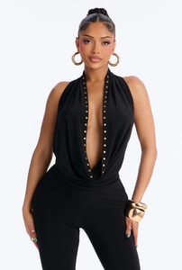 Detail of deep V-neck halter top with golden rivet accents on black fabric