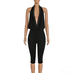Detailed front view of black halter neck jumpsuit with silver metal eyelet studs on neckline