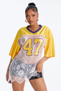 Detailed texture of white lace stitching and purple V-neck on jersey style T-shirt