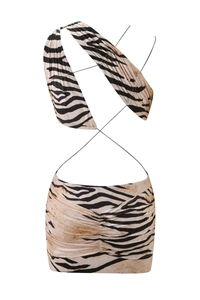 Detail of zebra print two-piece set featuring halter criss-cross top and ruched mini skirt