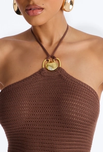 Detailed macro shot of brown knit dress featuring a gold shell neck ring and hollow texture