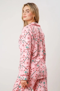 Detail view of pink Christmas pajama set with peppermint candy patterns and red piping trim