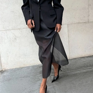 Street style shot of a black double-layered mesh midi skirt with high waist and side slit