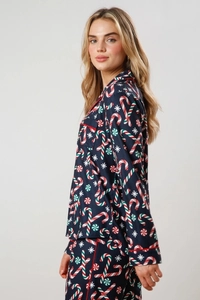 Close-up of Christmas pajamas featuring candy cane prints and red piping on navy fabric