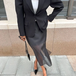 Detail of elegant black blazer with matching layered mesh midi skirt and sheer split design