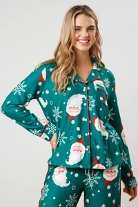 Detail of green Christmas pajamas set with Santa and snowflake patterns and red piping