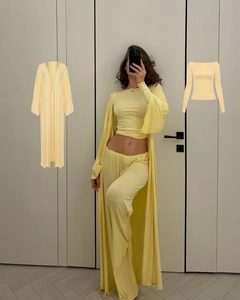 Detailed knit texture of a cream yellow three-piece cardigan, crop top and wide-leg trousers