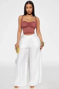 Detail of rose pink bandeau top with woven straps and white wide-leg high-waist trousers