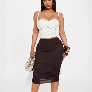 White sleeveless crop top with rope straps paired with a ruched brown high waist skirt