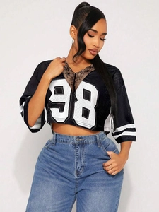 Détail du col en V en dentelle et du numéro 98 imprimé sur le tee-shirt en maille noire