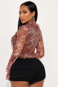 Detail view of animal print mesh top with ruffles and high-waist pleated black shorts