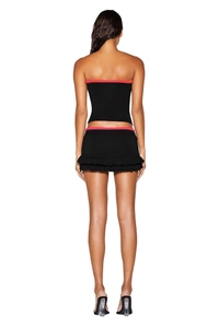 Detail of slim fit black tube top and ruffled mini skirt with pink contrast piping